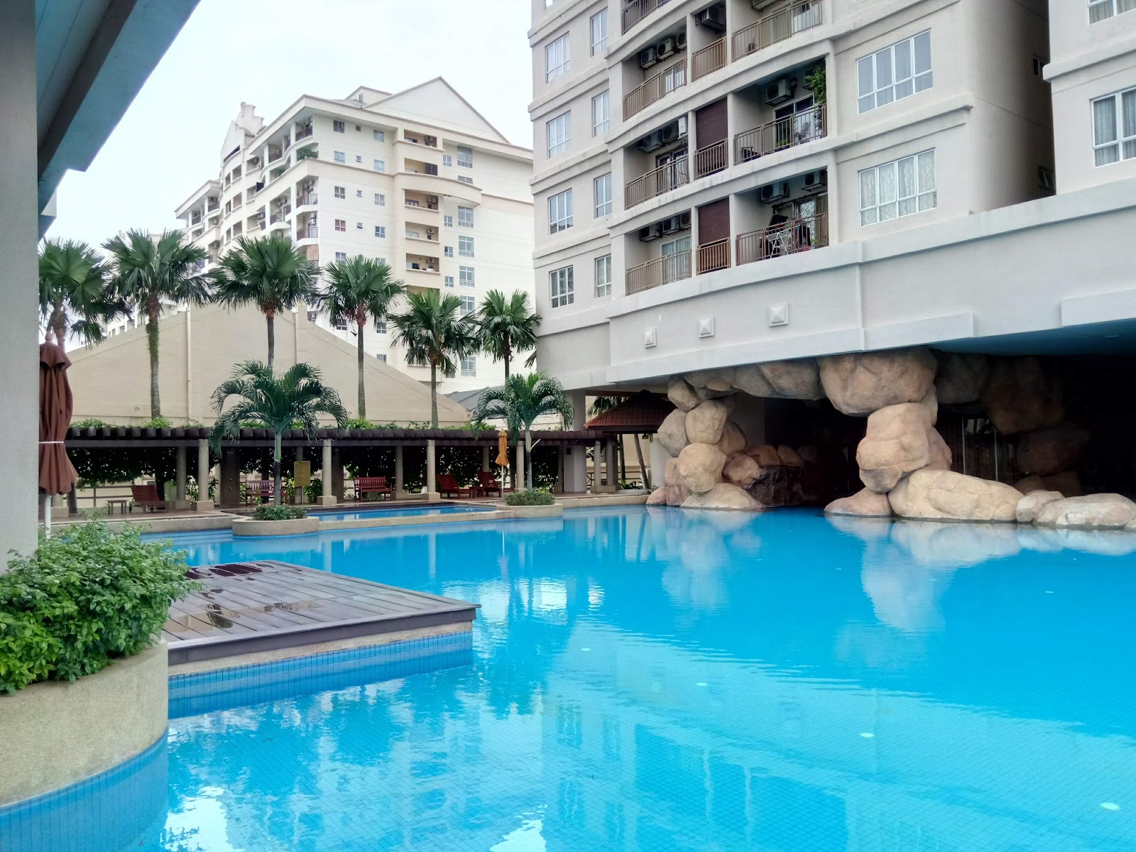 Windsor Tower: Swimming pool area with rock waterfall feature, surrounded by palm trees and residential tower blocks