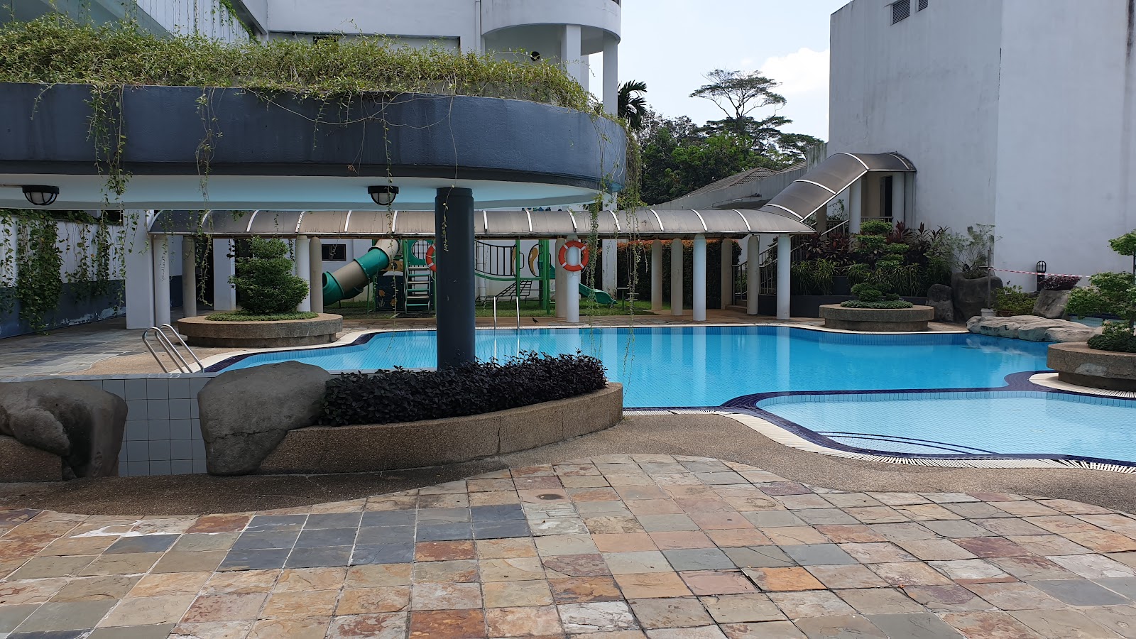 Casa Vista: Swimming pool area with children's playground slides, poolside pillars, and rock landscaping at a residential development