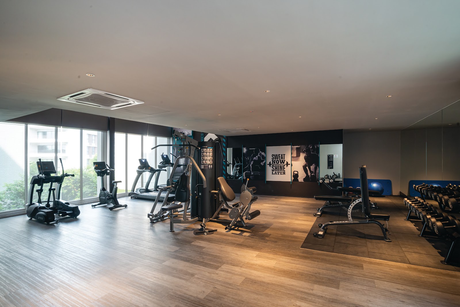 Utamara Boutique Residences: A gym room with treadmills, weight machines, dumbbells, and motivational wall graphics reading 'Sweat Now Shine Later'