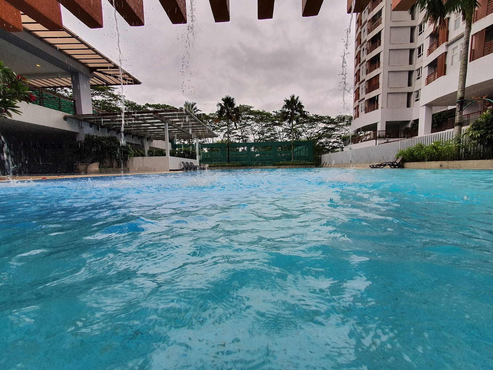 9 Bukit Utama: Swimming pool with water feature curtain, surrounded by residential buildings and palm trees