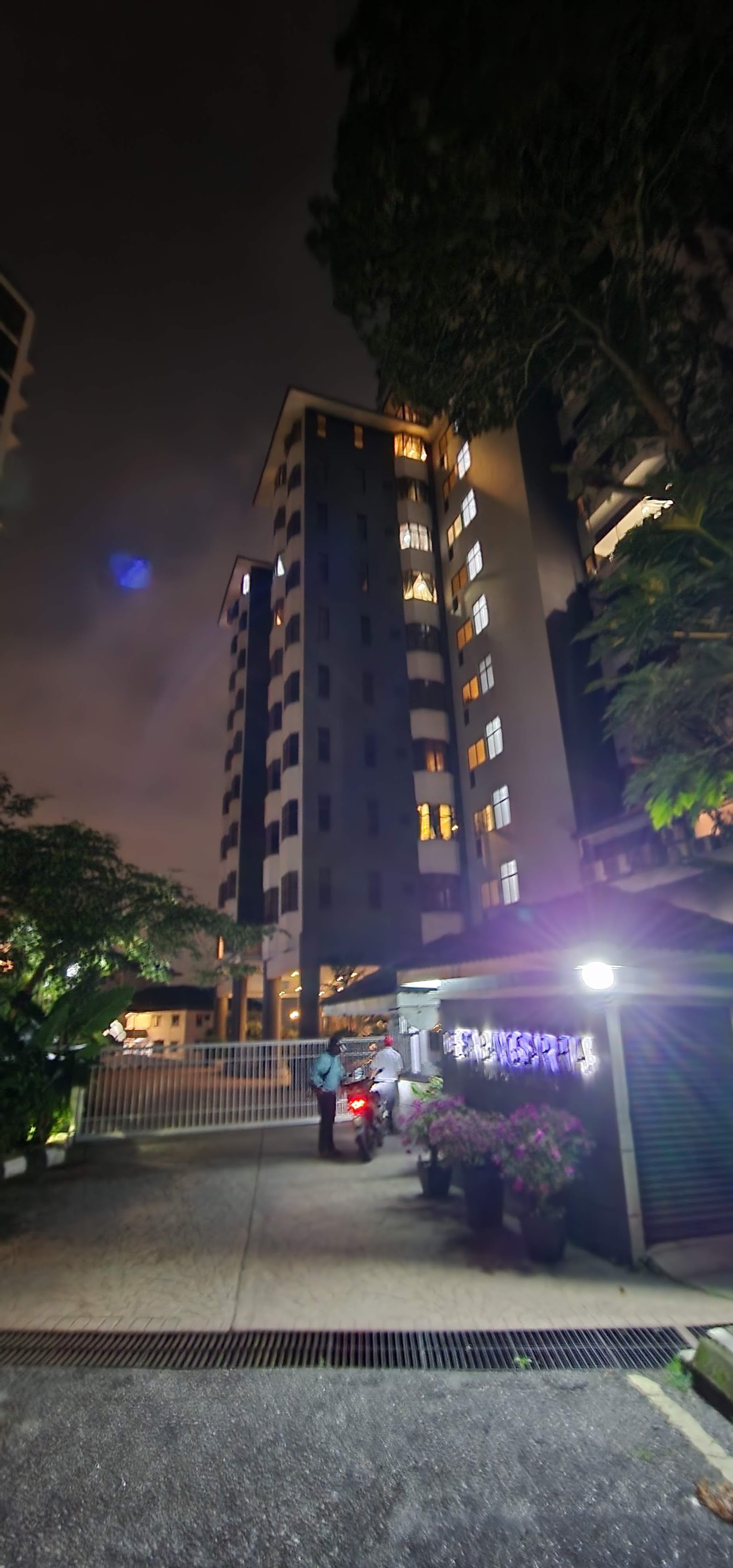 Desa Bangsar Ria: Nighttime view of a high-rise residential tower with lit windows, trees, and a lit signage area at the entrance