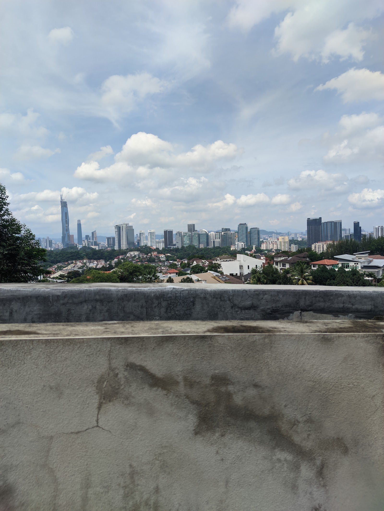 12 Kapas: City skyline view with skyscrapers and residential neighborhood, seen over a concrete parapet wall