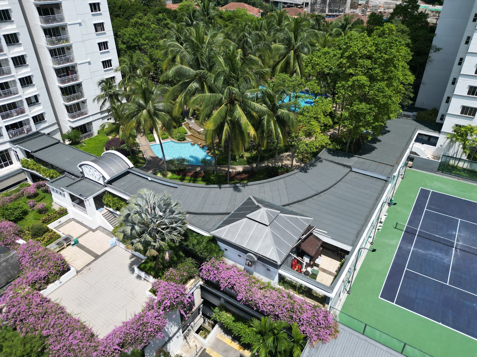 Kiaramas Sutera: Aerial view of a condominium's shared facilities including a swimming pool surrounded by palm trees and a tennis court, seen from above