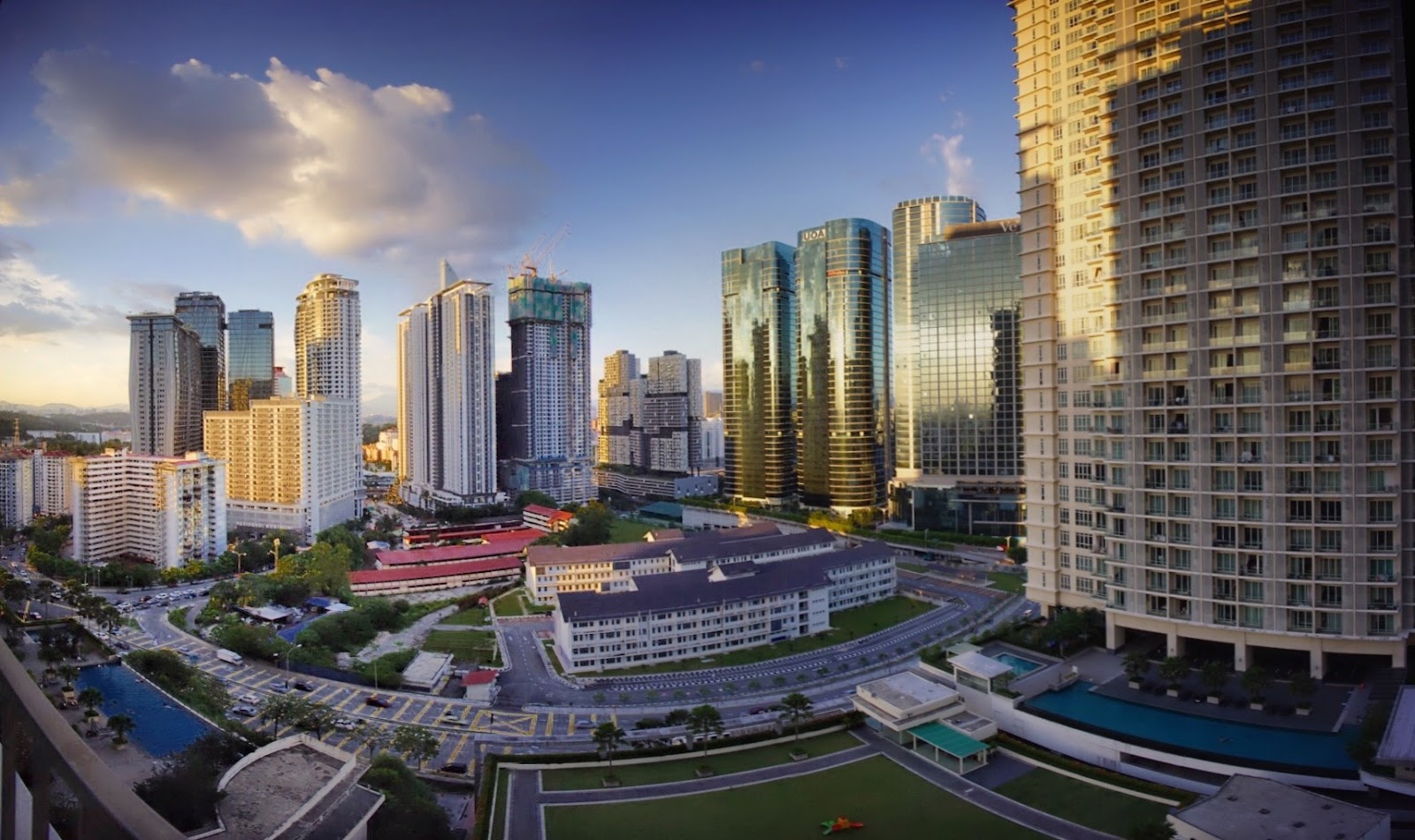 South View: Aerial view over a city skyline with numerous skyscrapers and mid-rise buildings under a blue sky at sunset, taken from an upper floor of a high-rise development