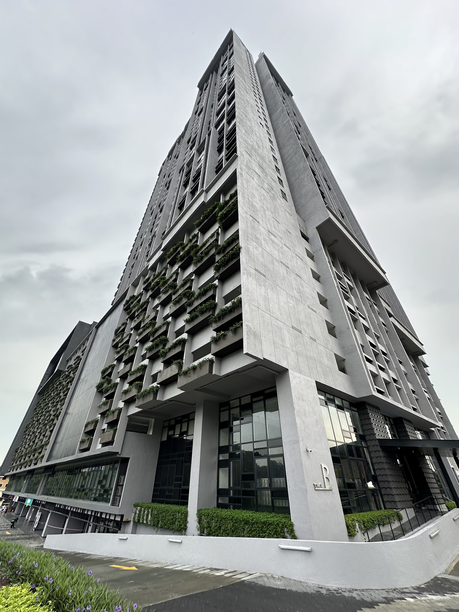 Cubic Botanical: Tall high-rise residential tower with vertical concrete fins and planted balconies, viewed from ground level