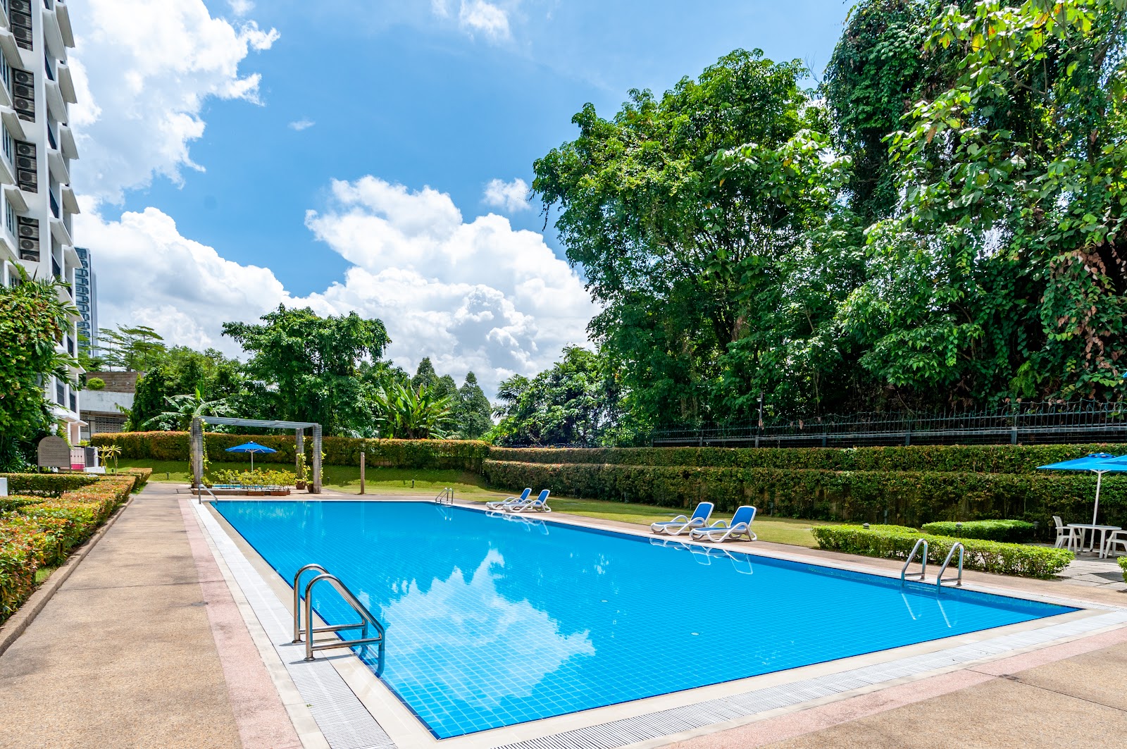 Wedgewood Residences: Outdoor swimming pool with lounge chairs and umbrellas surrounded by greenery at a residential complex