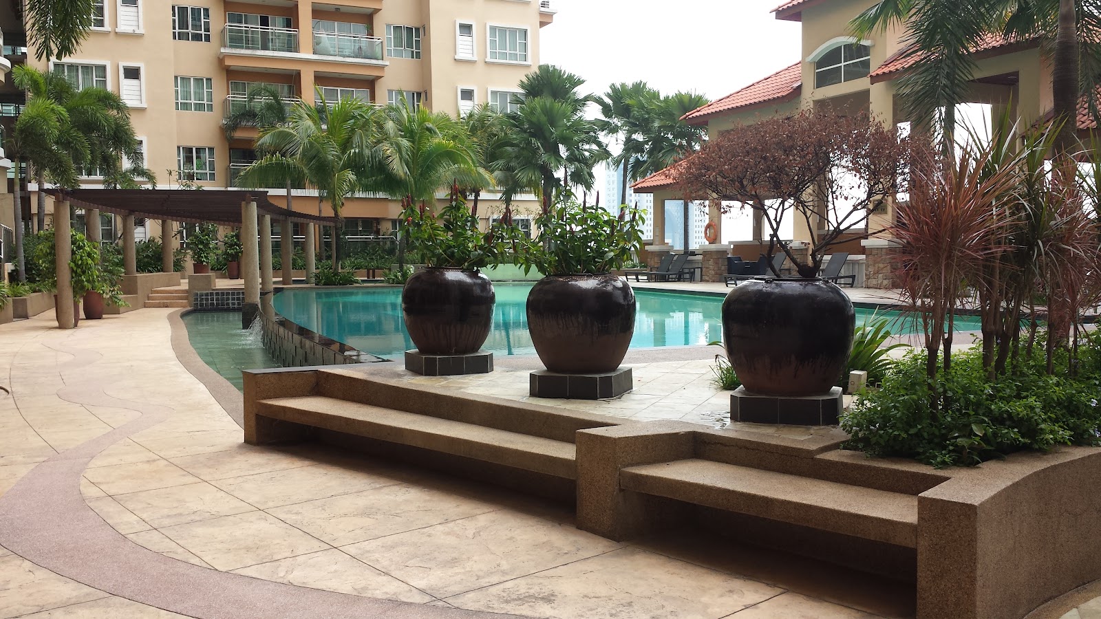 Hartamas Regency 2 Mont Kiara: Outdoor swimming pool area with large decorative pots, wooden pergola, and residential towers in the background