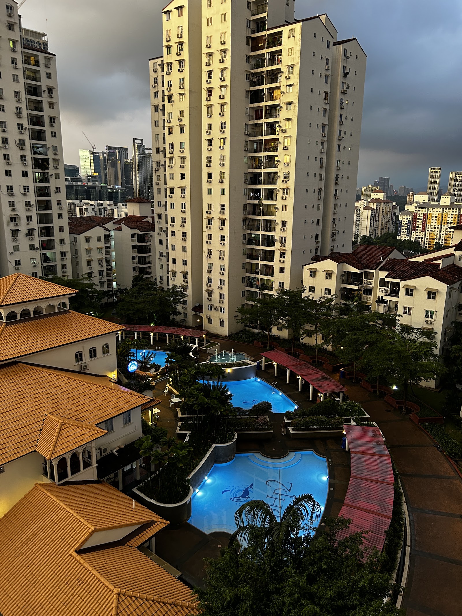 Pantai Hillpark 2: Aerial view of the pool area with fountain features, surrounded by high-rise apartment towers and a red-tiled roof clubhouse in the foreground