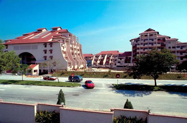 Trellises: View of a residential development complex with distinctive curved red-roofed buildings, seen from the street with cars passing by