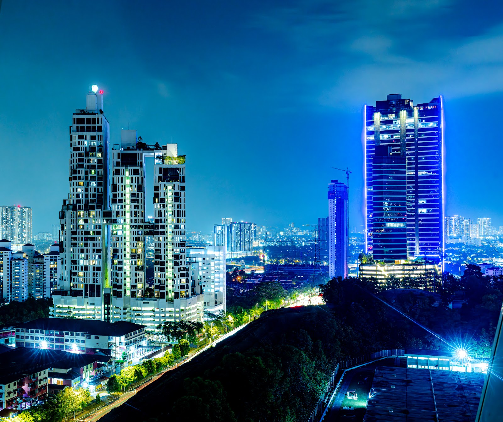Icon Residence: Night skyline view of high-rise residential towers illuminated with blue lighting, with cityscape in the background
