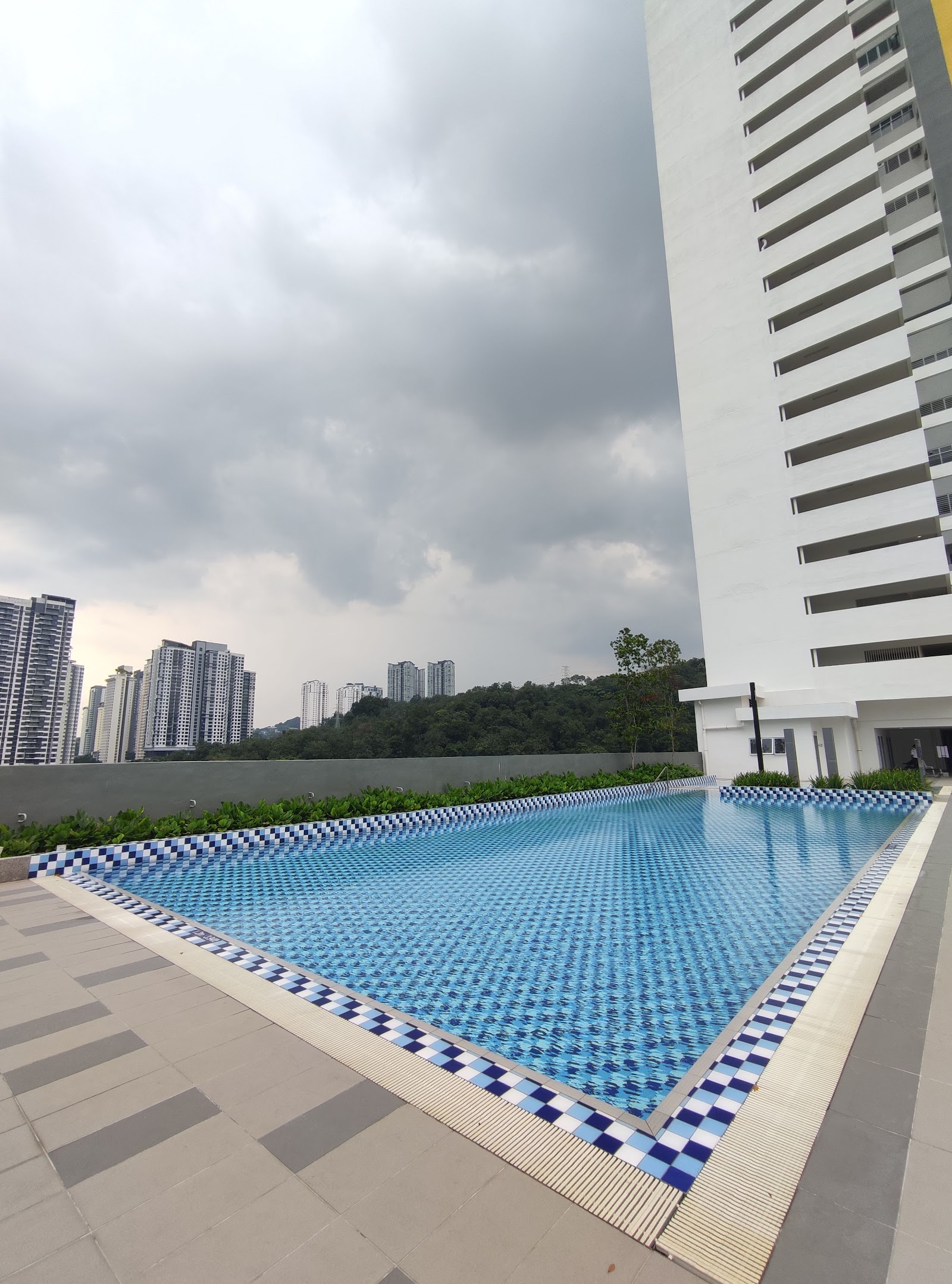 Kiara Kasih: An infinity-edge swimming pool at a residential development, with a city skyline and hills visible in the background