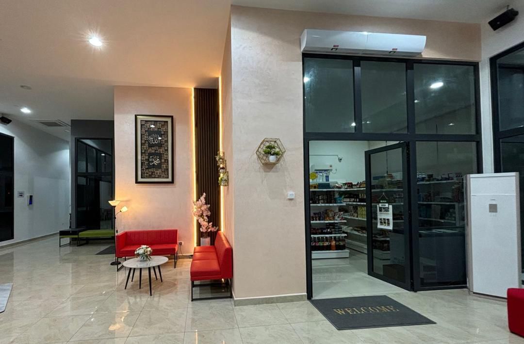 Residensi Cahaya: Lobby area with red seating, decorative plants, and an adjoining convenience store visible through glass doors