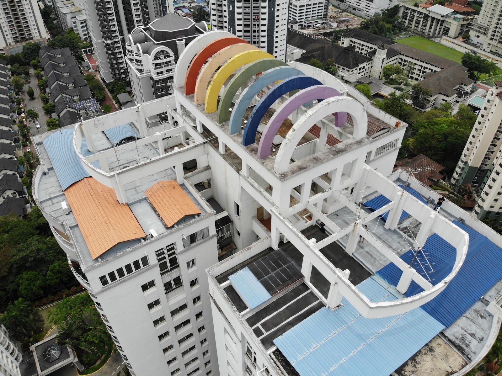 Mont Kiara Pelangi: Aerial view of a rooftop with colorful rainbow-arch structures atop a building, surrounded by other high-rise buildings and greenery