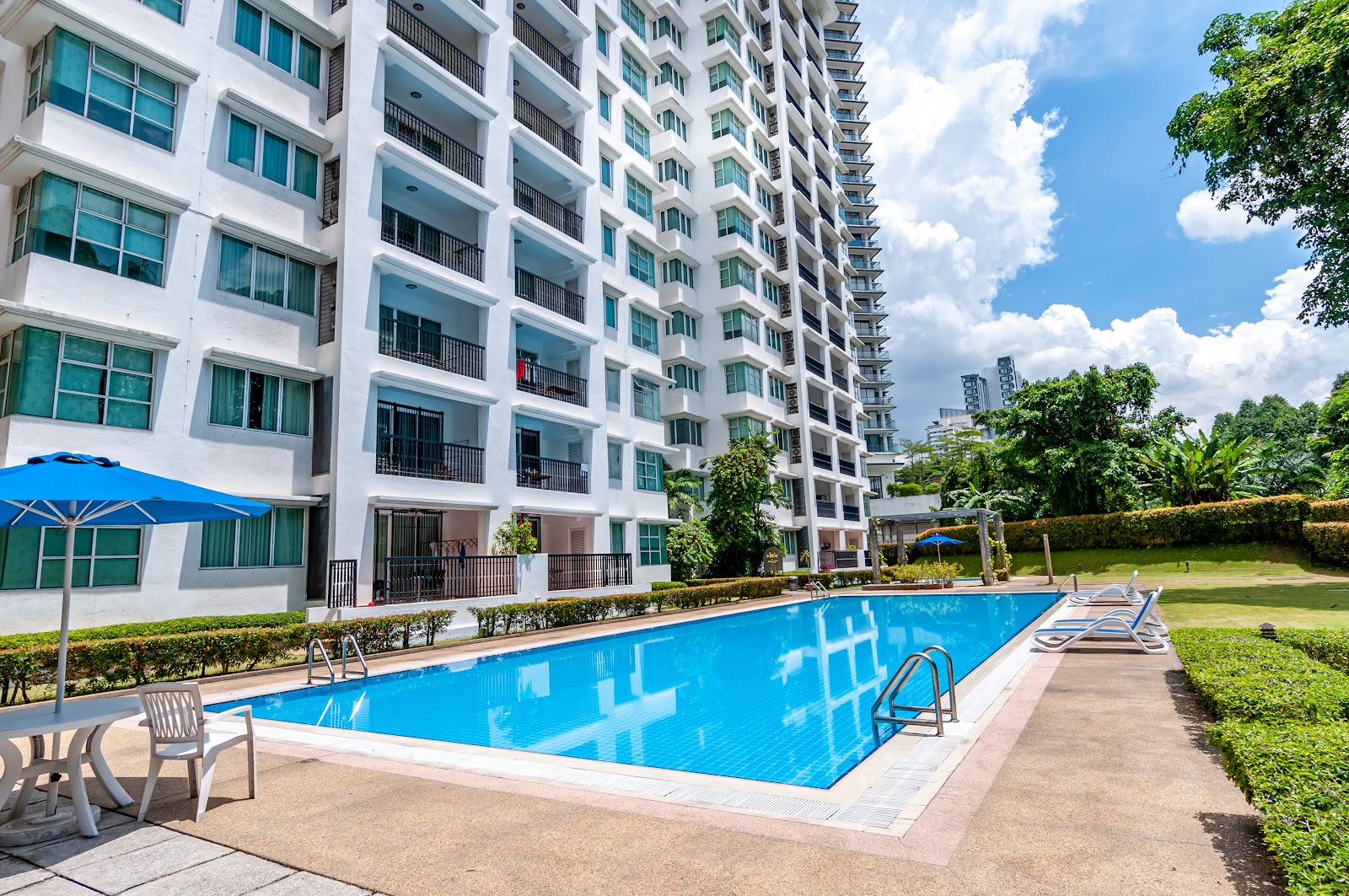 Wedgewood Residences: Swimming pool with sun loungers and umbrella in front of a high-rise residential building