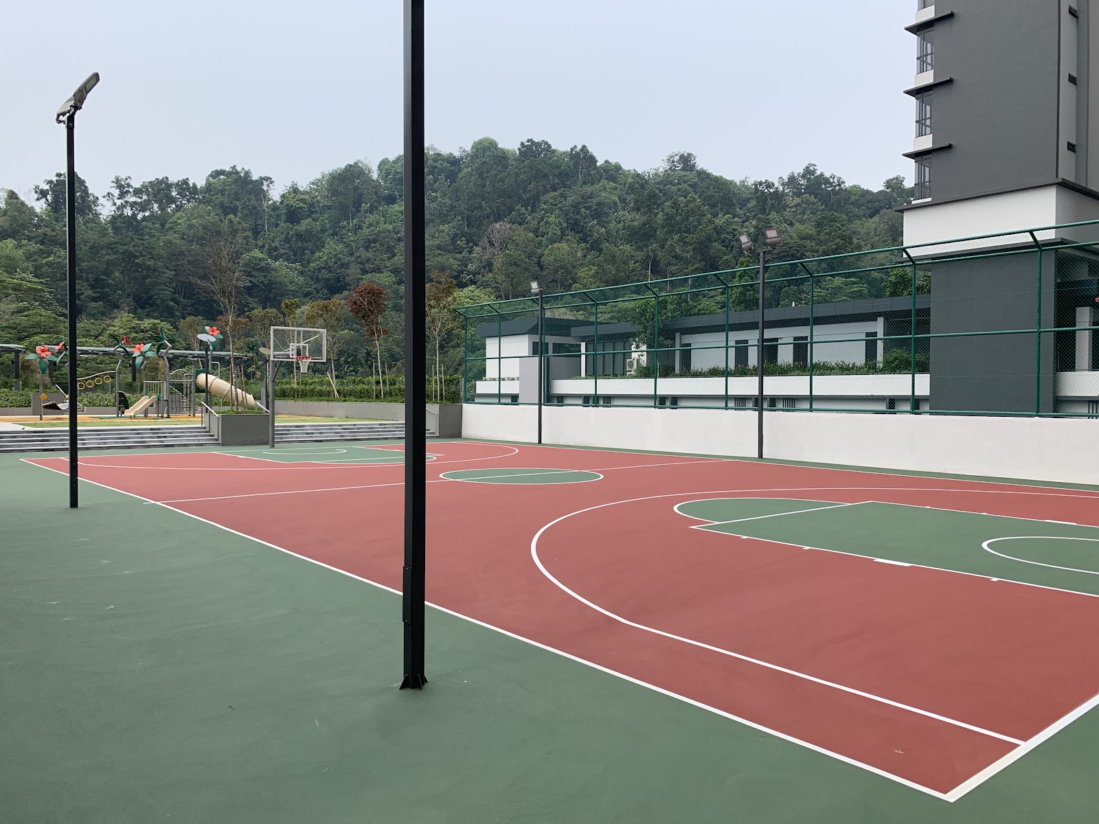 Secoya Residences @ Pantai Sentral Park: An outdoor basketball court with a playground area in the background, surrounded by greenery and a residential tower