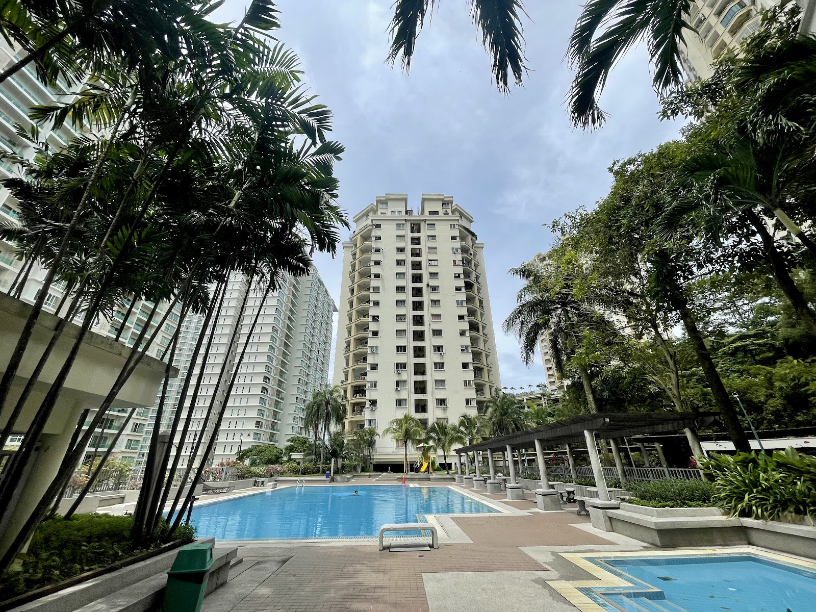 Pantai Panorama Condominiums: View of a high-rise residential tower surrounded by palm trees, with a swimming pool visible in the foreground courtyard