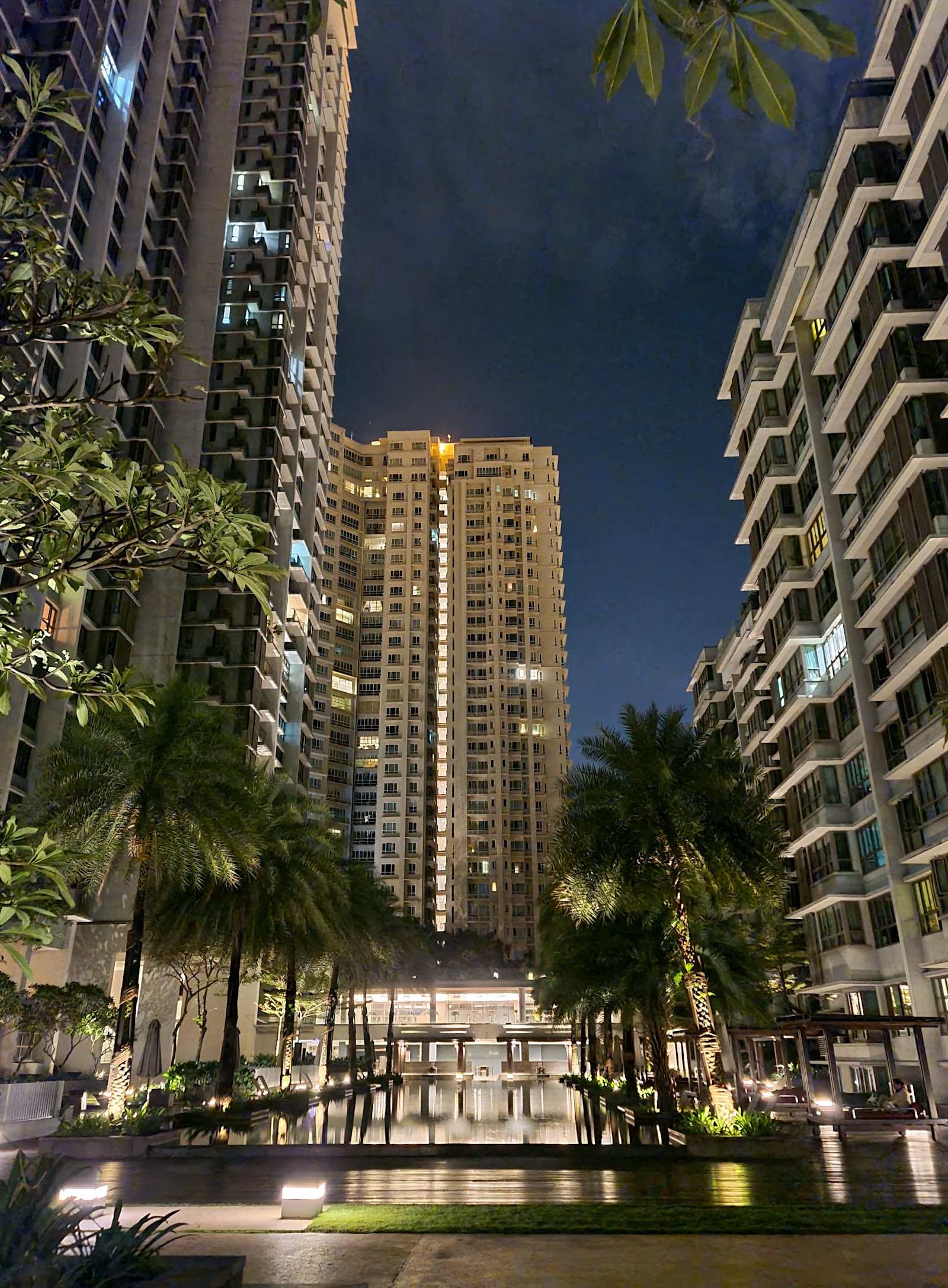 Seni Mont Kiara: Nighttime view of high-rise residential towers with palm trees and a courtyard water feature between buildings