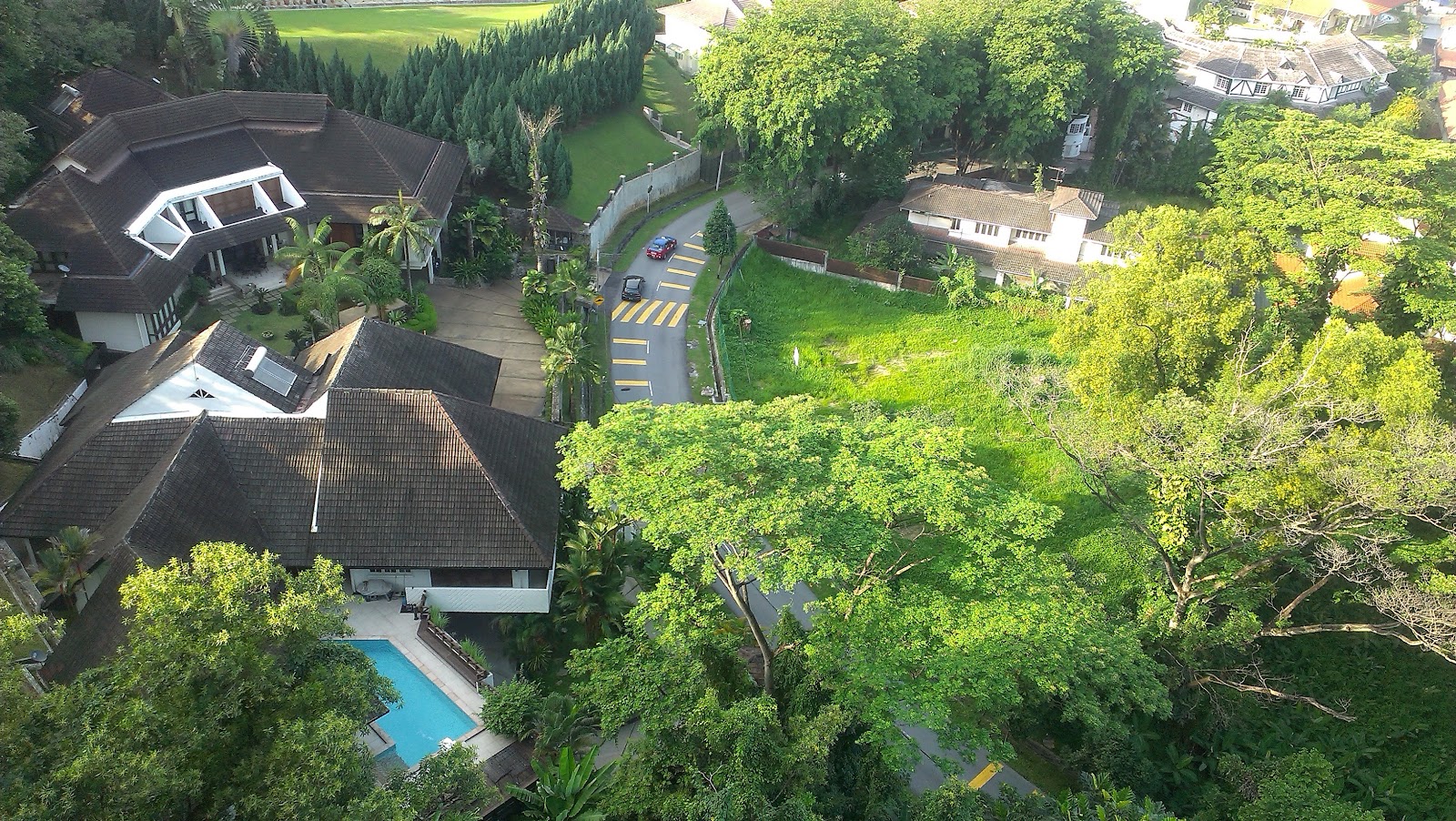 Contessa: Aerial view of a residential property with tiled roofs, a swimming pool, surrounding trees, and a driveway leading to a street