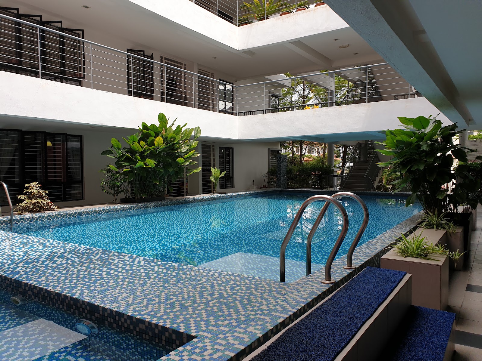 Laman Ara Utama: Swimming pool with steel handrails in the courtyard of a residential building, surrounded by plants and balconies