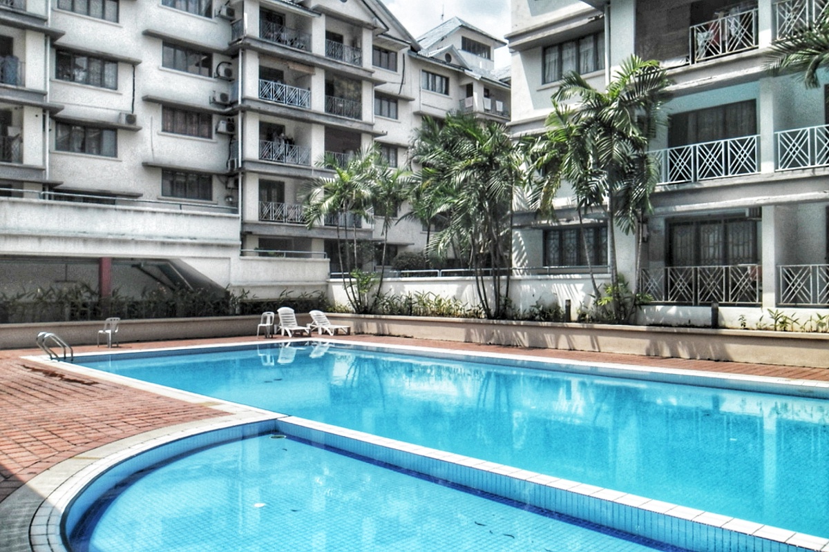 Bangsar Permai: Swimming pool area with lounge chairs surrounded by residential apartment buildings and palm trees