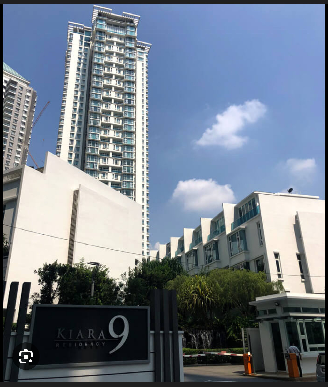 Kiara 9 Residency: Tall residential tower with entrance sign reading 'Kiara 9 Residency' in front, alongside low-rise buildings and a security checkpoint