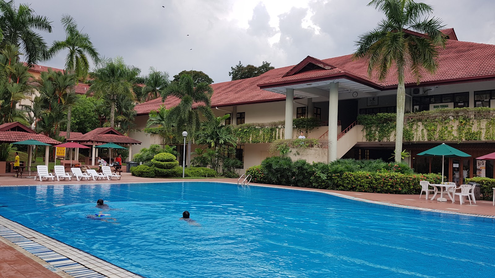 Kiara Park: Outdoor swimming pool with loungers, umbrellas and seating area in front of a resort-style building with red tiled roof