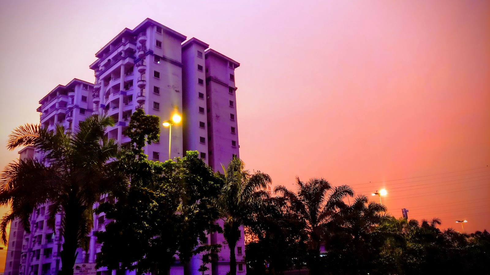 Vista Angkasa: High-rise residential towers viewed from outside at sunset, with palm trees in the foreground and a street lamp lit