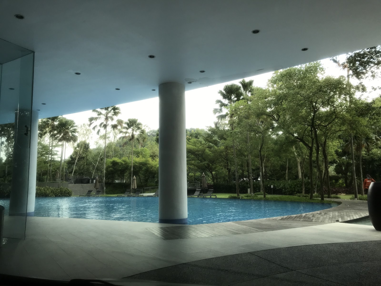 Sunway Palazzio: Poolside area under a covered walkway with a large pillar, surrounded by lush trees and greenery