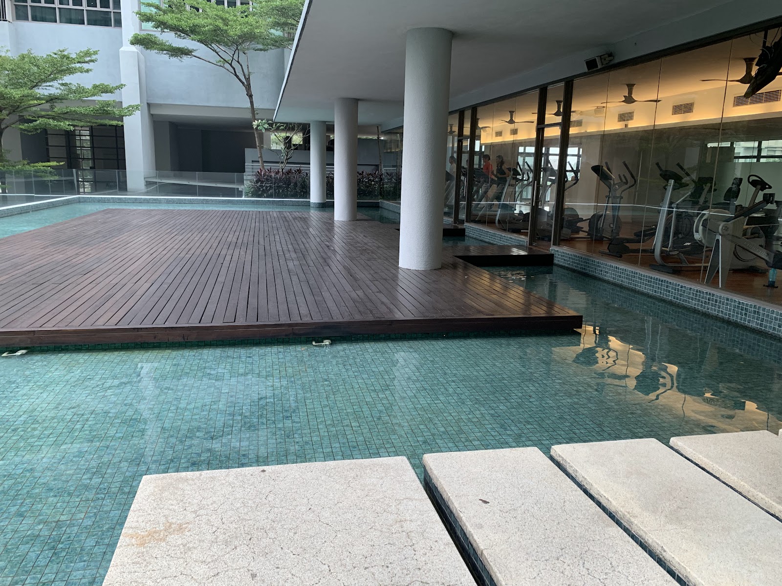 Seni Mont Kiara: Pool deck with wooden platform next to a swimming pool, with a gym visible behind glass panels