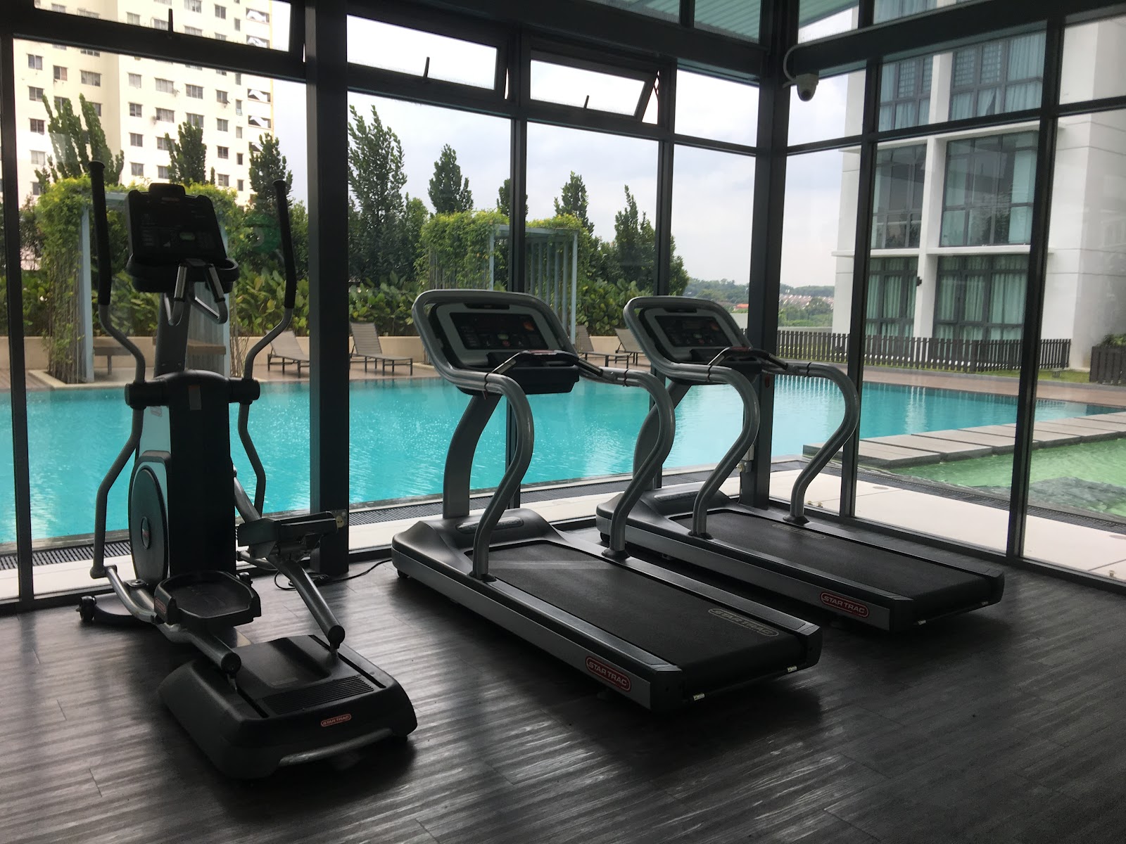Boulevard Residence: Indoor gym with treadmills and elliptical machine overlooking an outdoor swimming pool