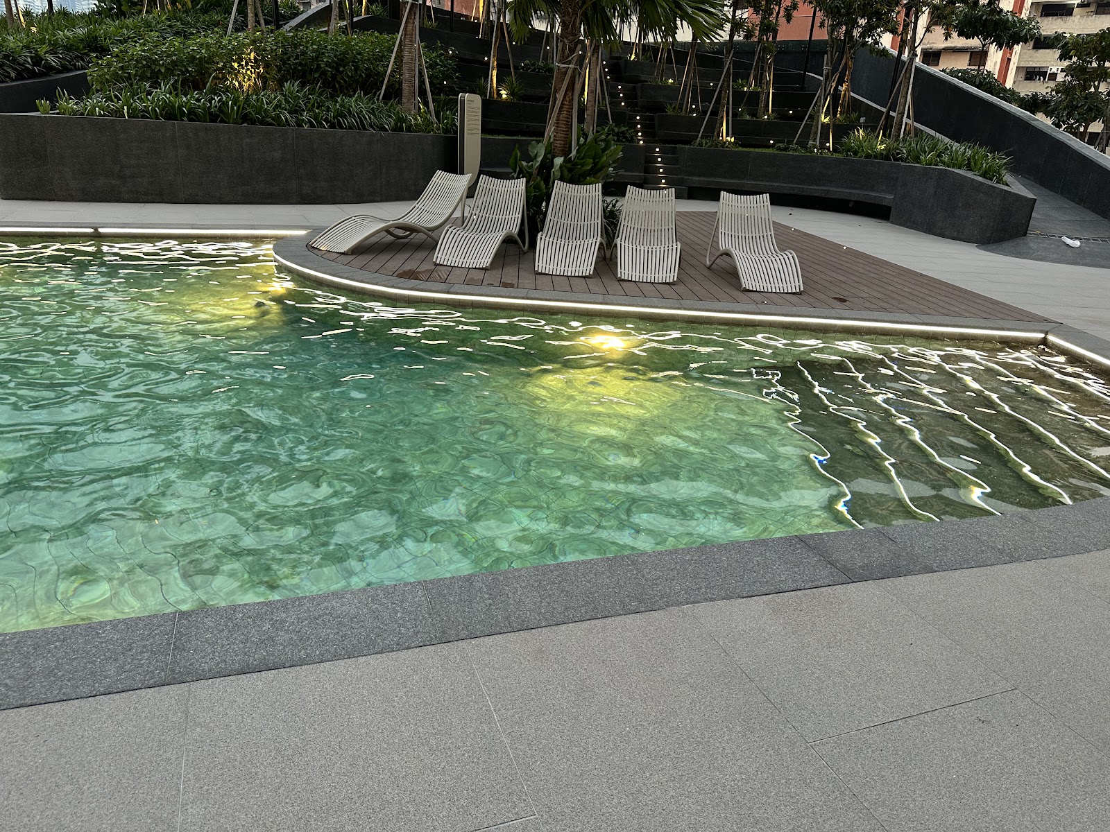 Bangsar Hill Park: Swimming pool with lounge chairs on a wooden deck at a residential development, surrounded by landscaped greenery