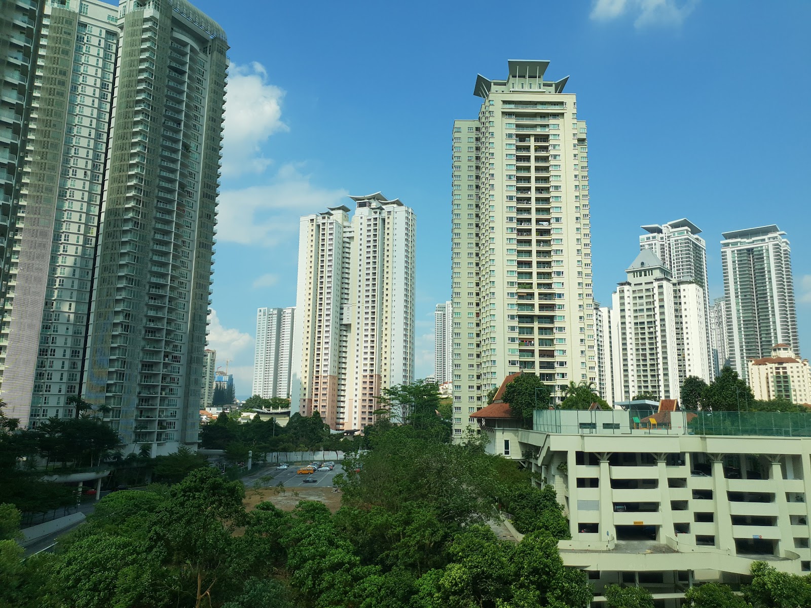 Aston Kiara 3: View of surrounding high-rise condominium towers and cityscape with greenery below, seen from a building's exterior vantage point
