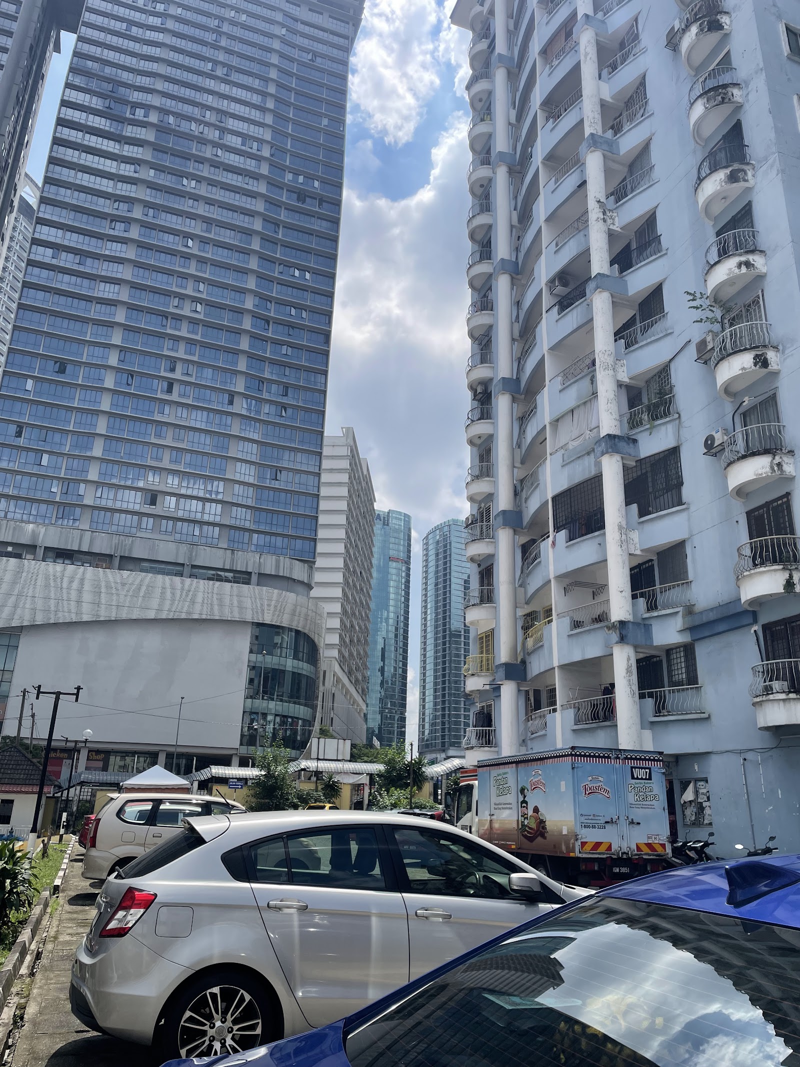 Vista Angkasa: Street-level view of tall residential and office buildings with cars parked in front