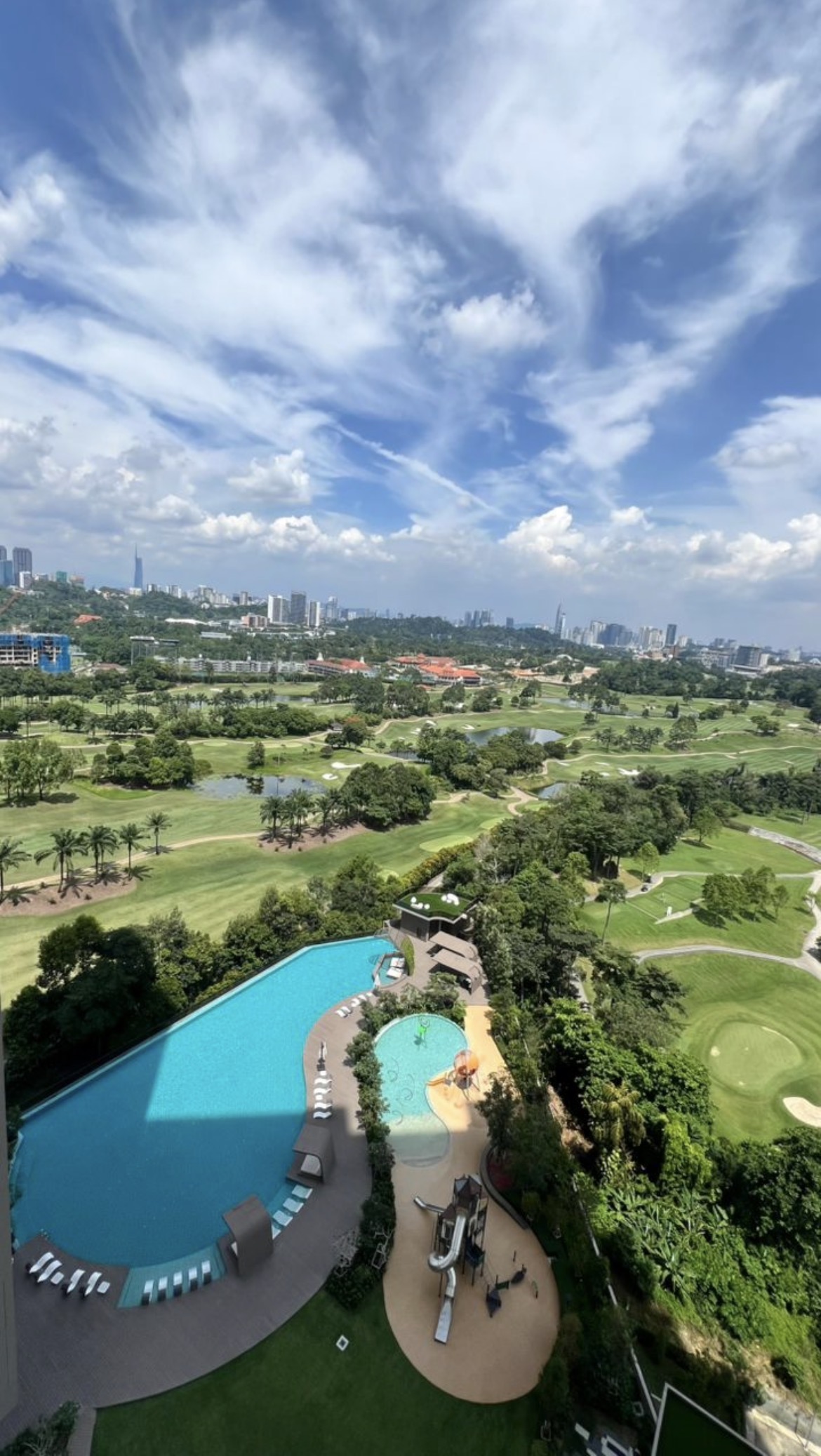 Jendela Residences: Aerial view of an infinity pool and playground at a residential development overlooking a golf course and city skyline