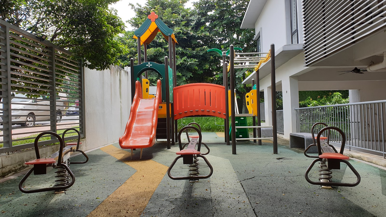 Laman Ara Utama: Children's playground with a slide, climbing structure, and spring rocker seesaws next to a residential building