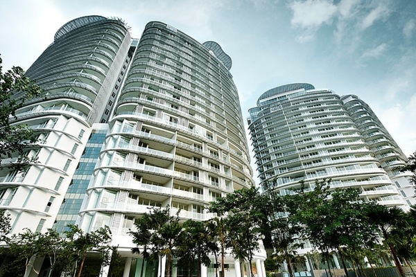 Sunway Palazzio: Low-angle view of tall curved residential apartment towers with balconies, surrounded by trees, against a blue sky