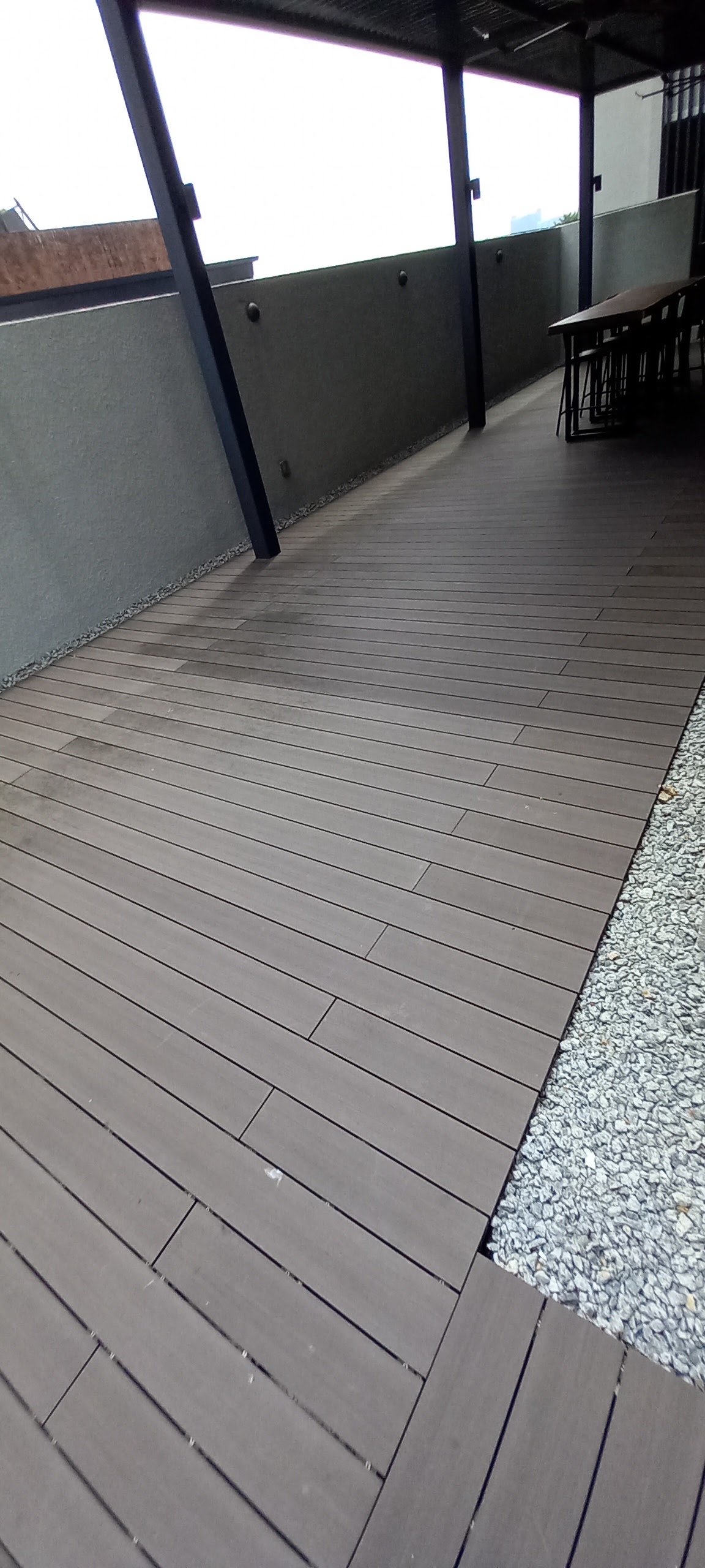 6 Kapas: Composite decking walkway on a rooftop terrace with gravel edging, columns, and seating area