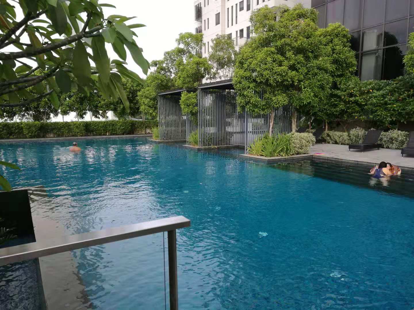Icon Residence: Outdoor swimming pool at a residential development with swimmers, lounge chairs, and surrounding greenery