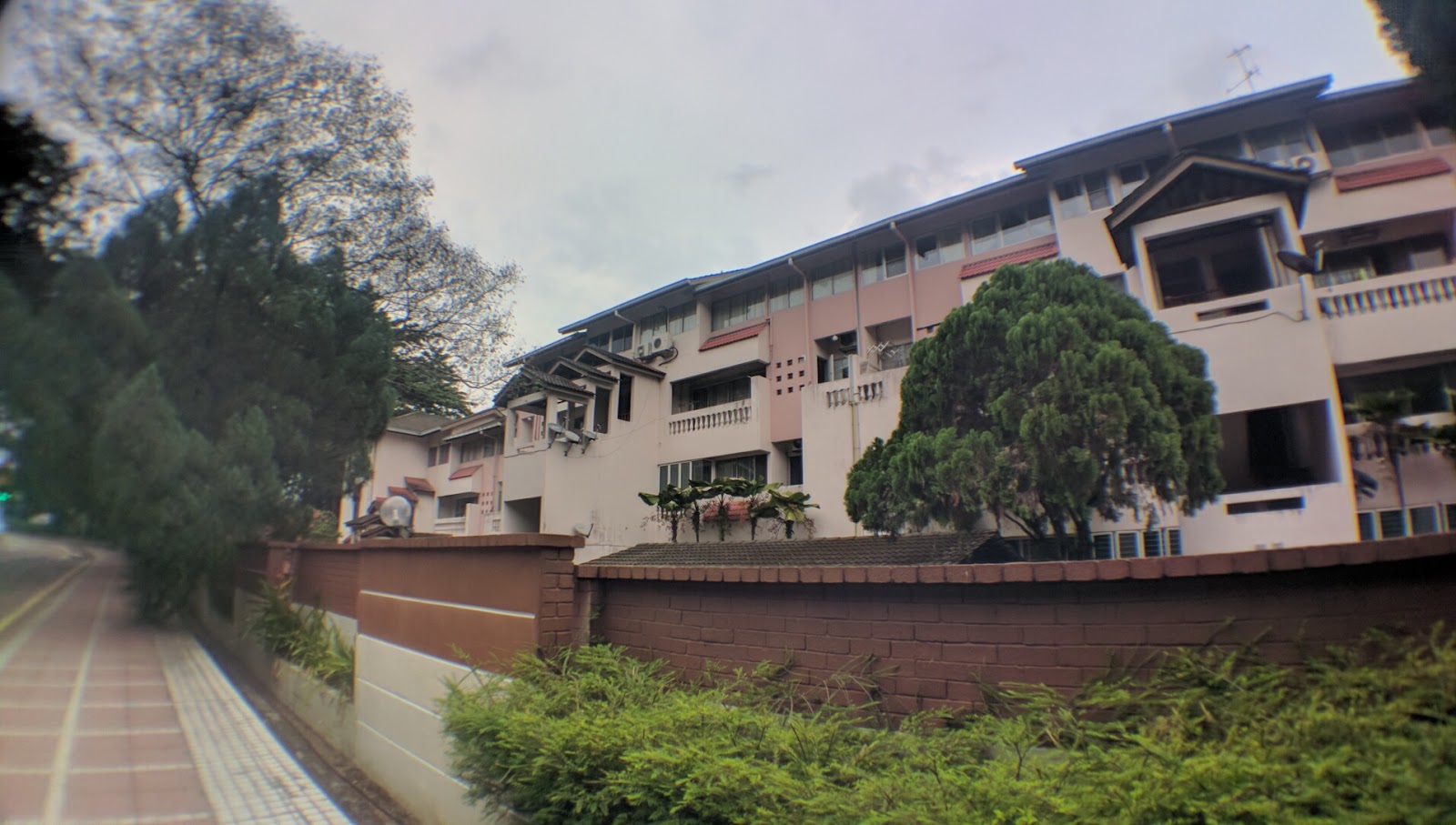 Kiara Green Townhouses: Exterior view of a low-rise apartment building with brick boundary wall, trees, and landscaped shrubs in front