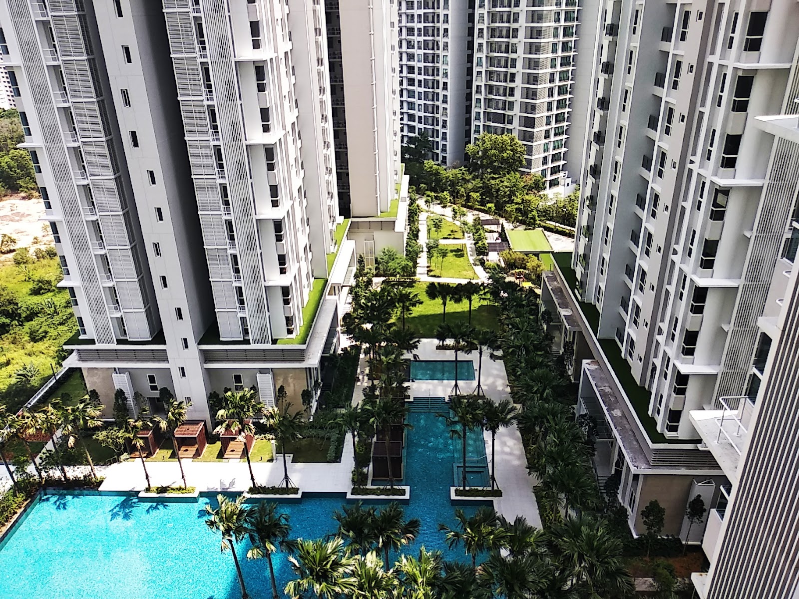 Pavilion Hilltop: Aerial view of residential towers with landscaped grounds featuring swimming pools, palm trees, and greenery between buildings