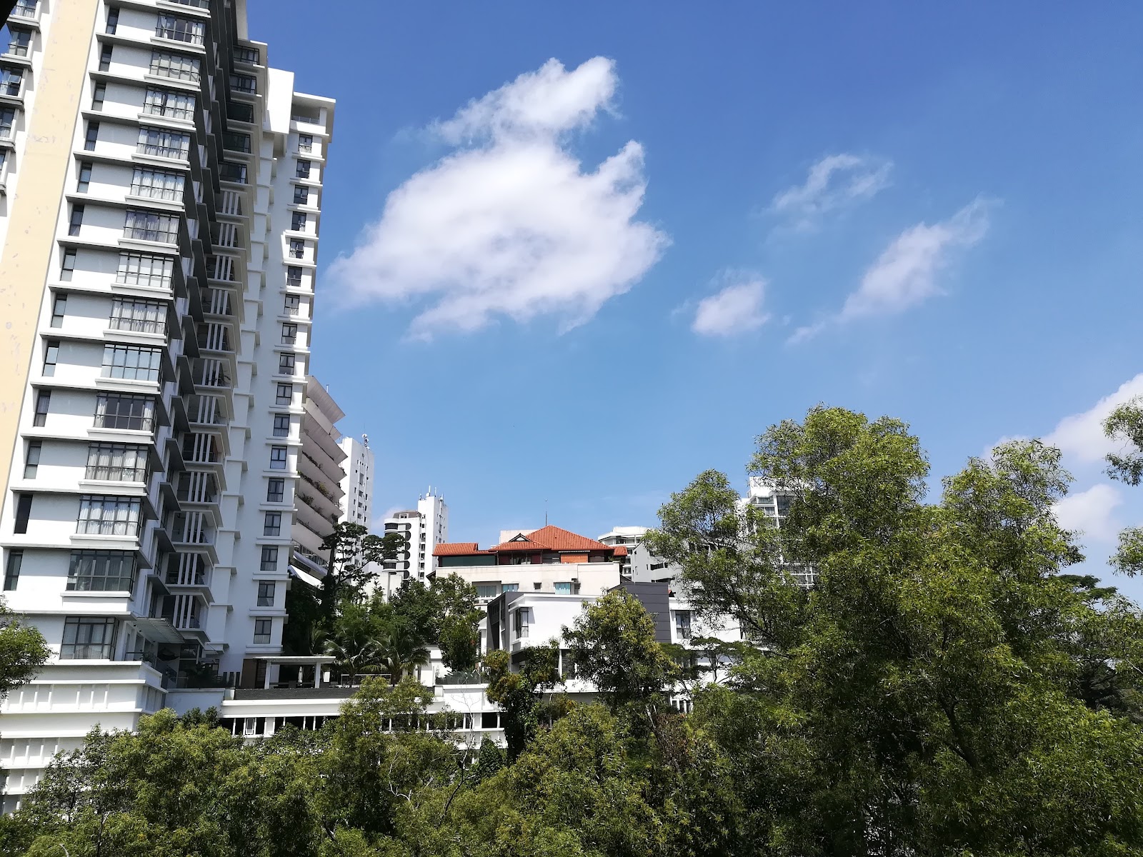 Cascadium: View of a high-rise residential tower exterior with surrounding buildings and trees under a blue sky