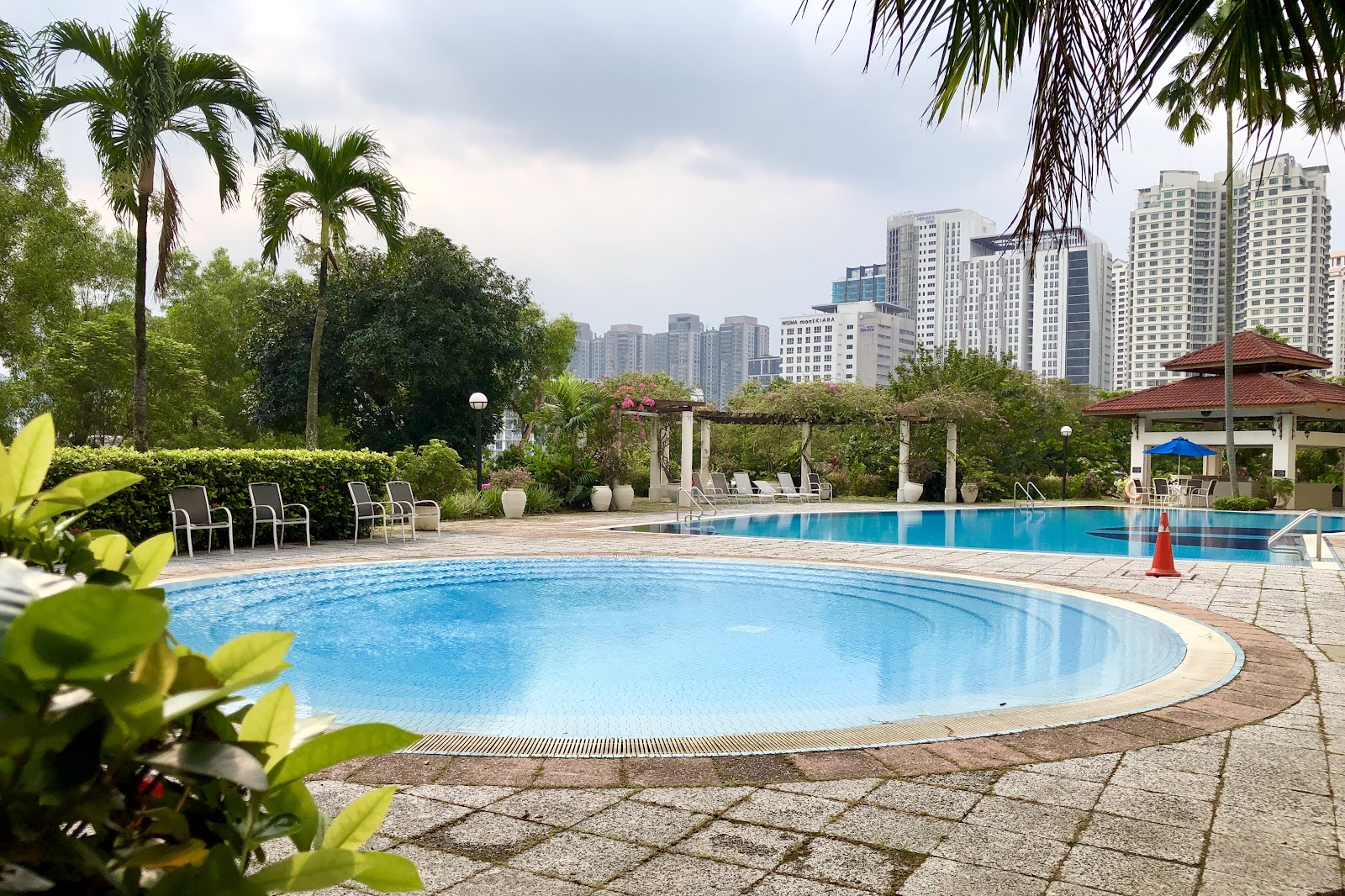 Menara Hartamas: An outdoor swimming pool area with lounge chairs, a gazebo, and city skyscrapers in the background