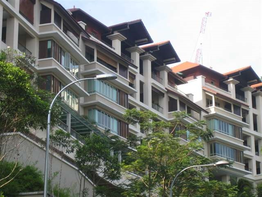Inara: Low-angle view of a multi-story residential condominium building with tiled roofs, balconies, and greenery in the foreground
