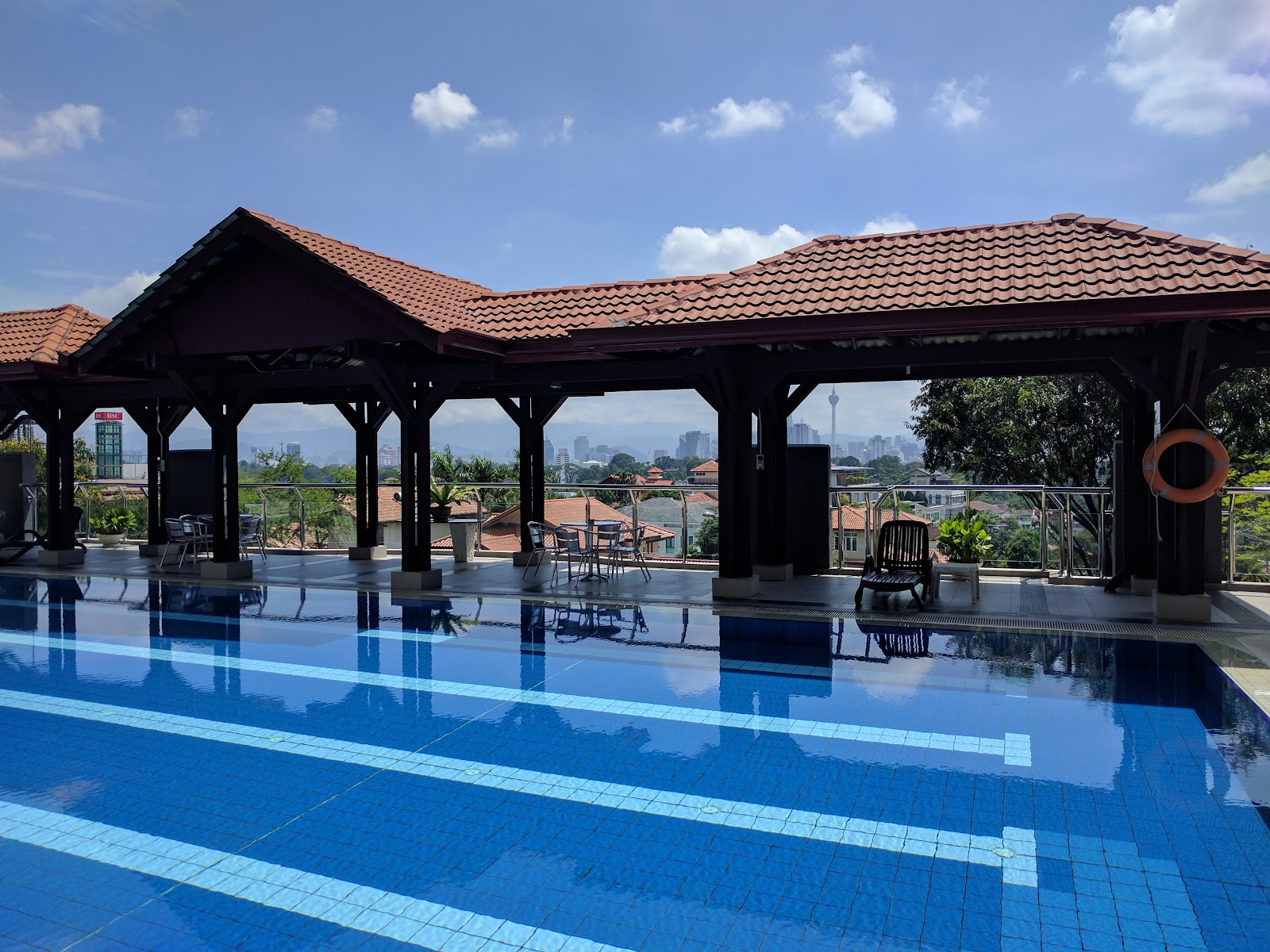 Cascadium: Rooftop swimming pool with tiled pavilion, lounge chairs, and a city skyline view in the background