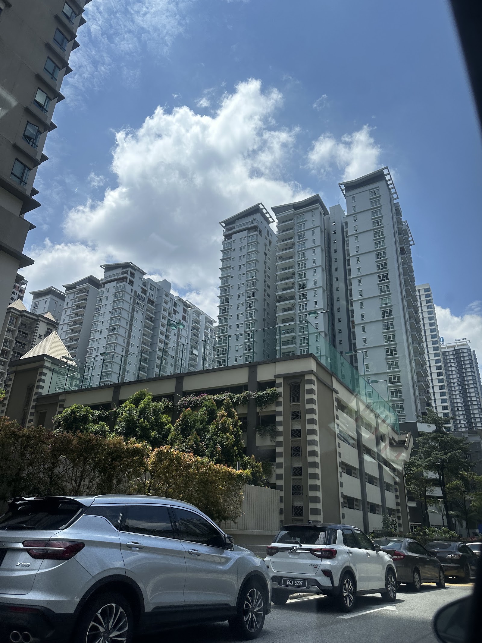 Ceriaan Kiara: Street-level view of high-rise residential towers with cars parked in the foreground