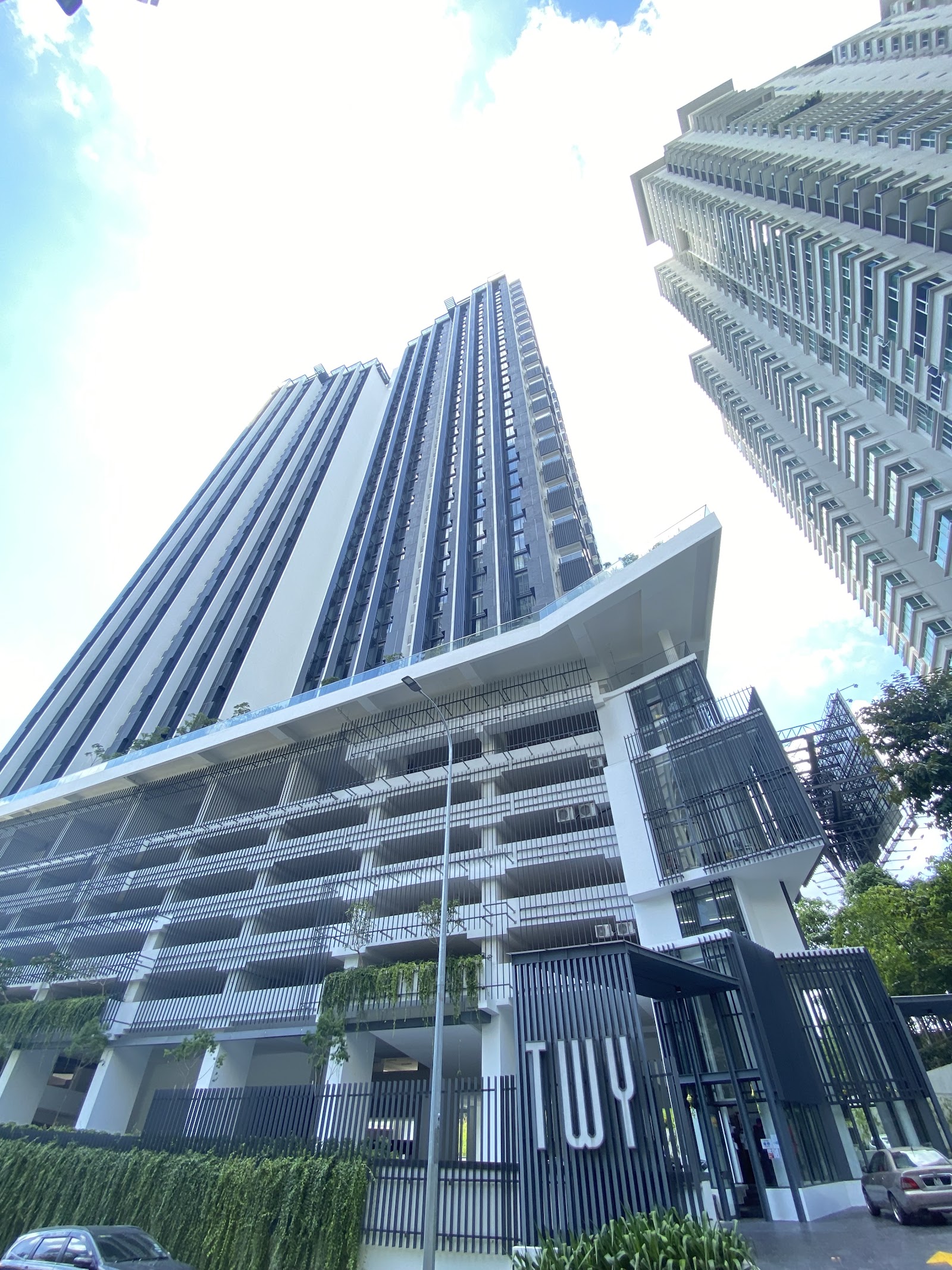 TWY Mont Kiara: Low-angle view of the TWY residential towers in Mont Kiara, showing the facade, balconies and entrance signage