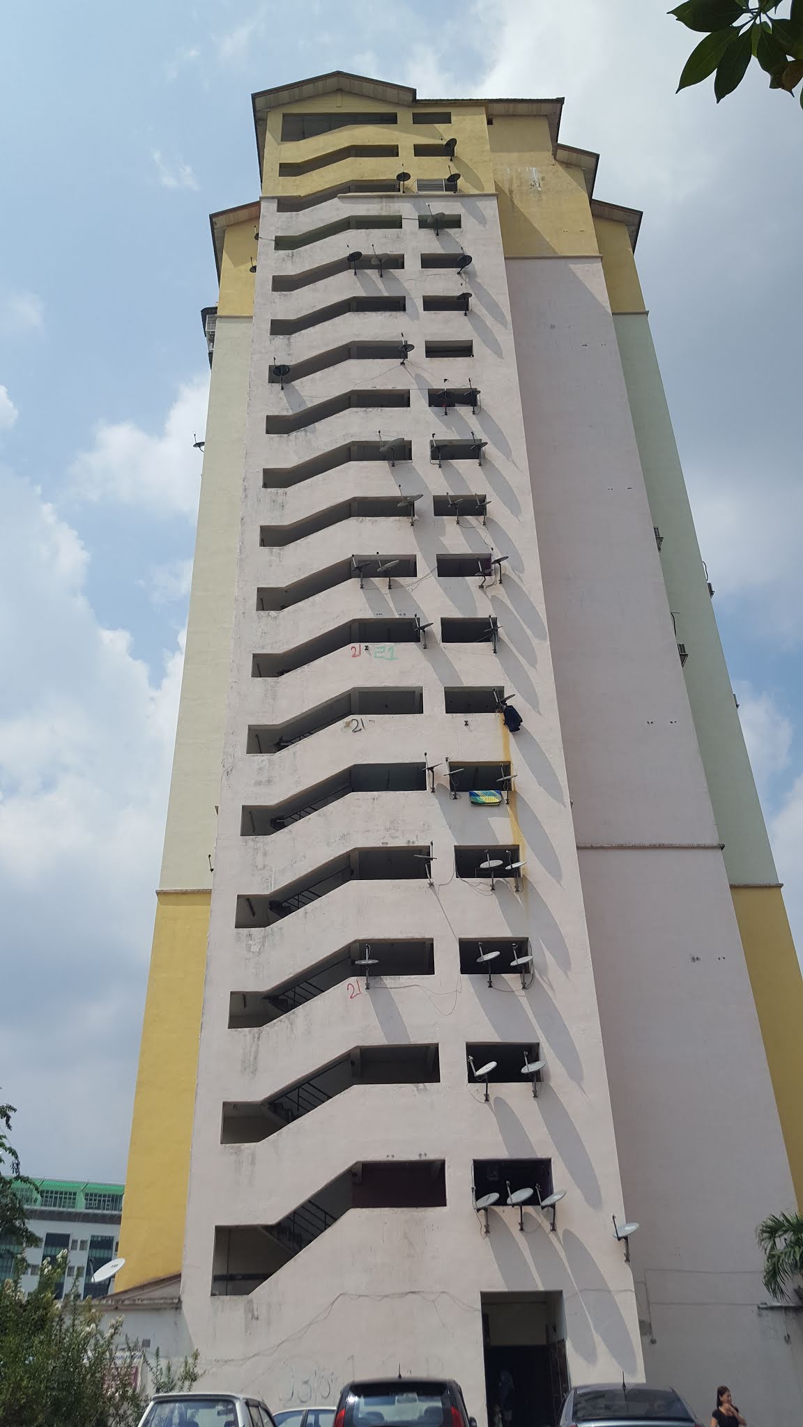Sri Ara Apartment: Tall residential apartment tower viewed from below, showing repeating floors with staircases, balconies and satellite dishes