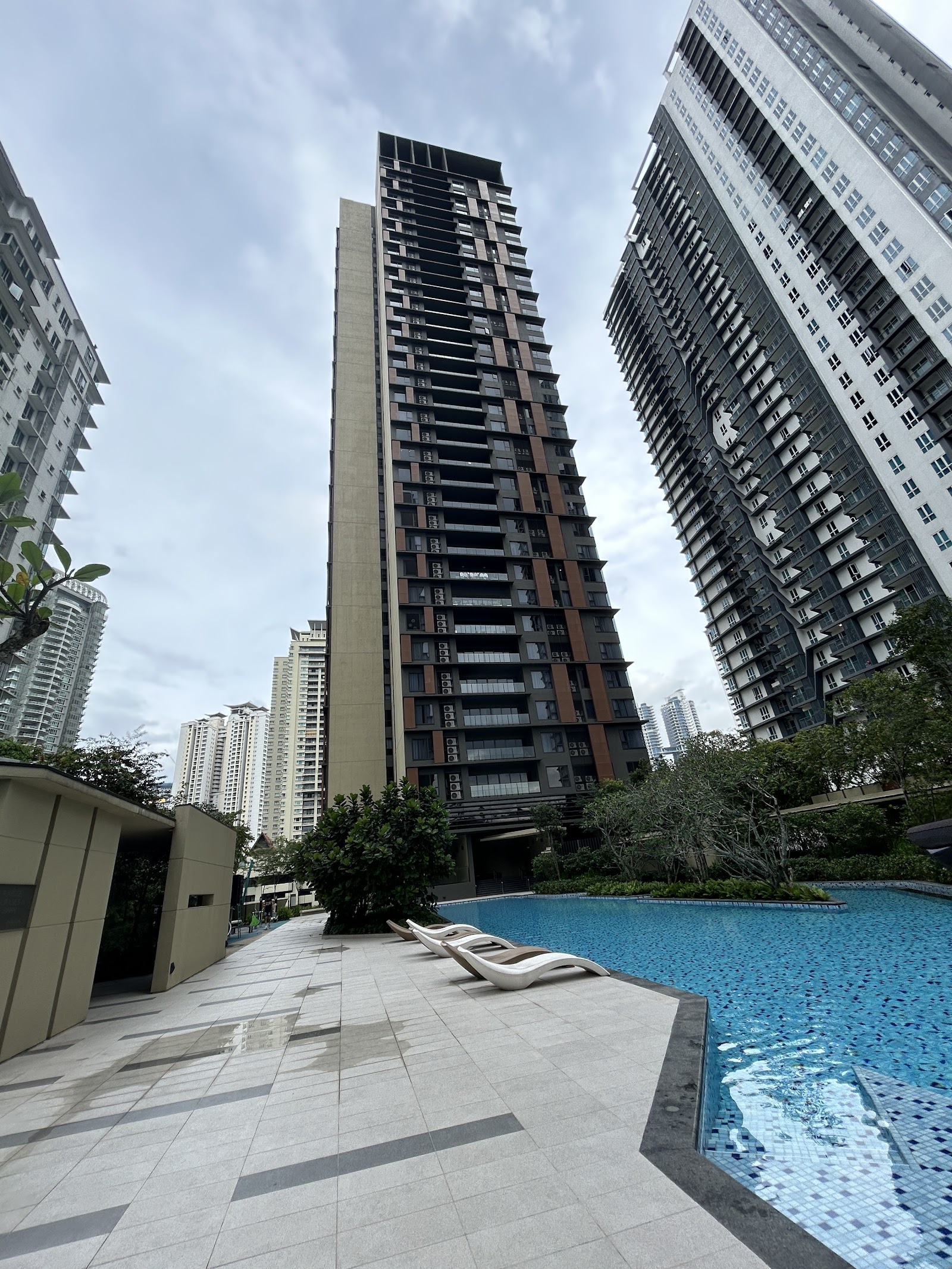 Aston Kiara 3: High-rise residential towers with a pool deck and lounge chairs in the foreground, surrounded by other high-rise buildings