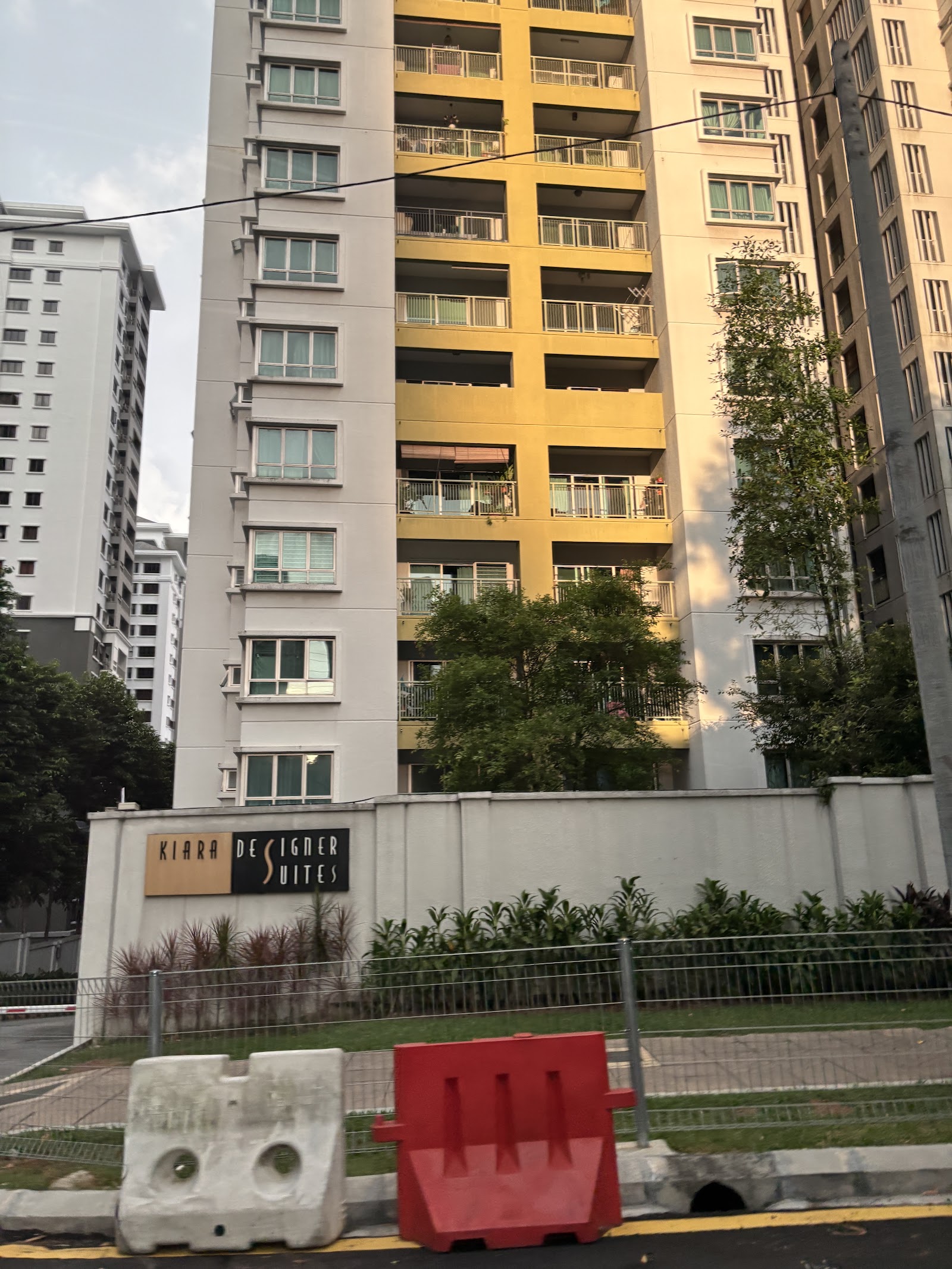 Kiara Designer Suites: Exterior view of Kiara Designer Suites apartment towers with a boundary wall and signage in front, other high-rise buildings visible nearby