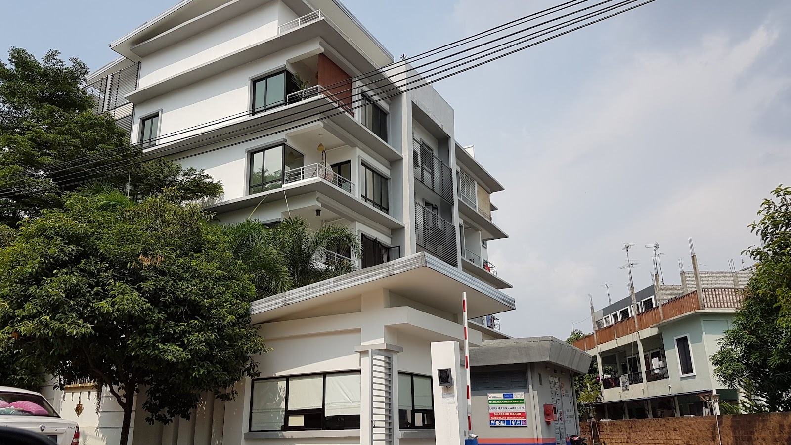 Laman Ara Utama: Street view of a modern multi-story residential building with balconies, trees, and cars parked in front